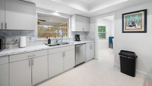 A modern kitchen with white cabinets, a marble countertop, and a black trash bin. - Spacious 3 Bedroom 2 Bath Walk to Eagle Lake Park Fenced Yard (Clearwater)