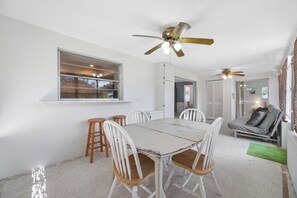 A dining area with a white table and chairs, a ceiling fan, and a window with a view of the outside. - Spacious 3 Bedroom 2 Bath Walk to Eagle Lake Park Fenced Yard (Clearwater)