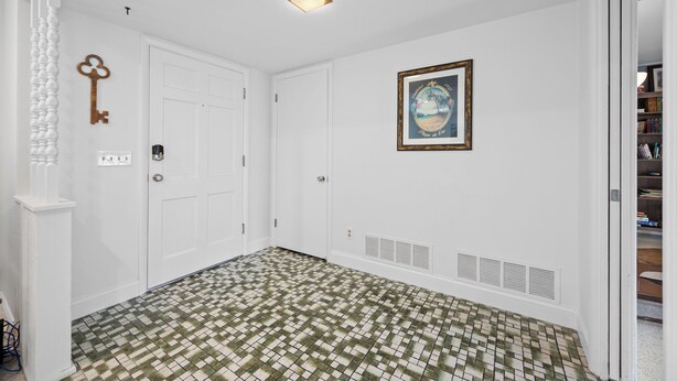 A hallway with a patterned floor, white doors, a key on the wall, and a framed picture. - Spacious 3 Bedroom 2 Bath Walk to Eagle Lake Park Fenced Yard (Clearwater)