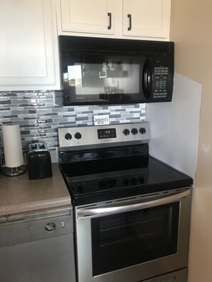Uma cozinha com fogão de aço inoxidável, micro-ondas e torradeira.
