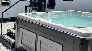 Een hottub met treden ernaartoe, omringd door een grindpad.