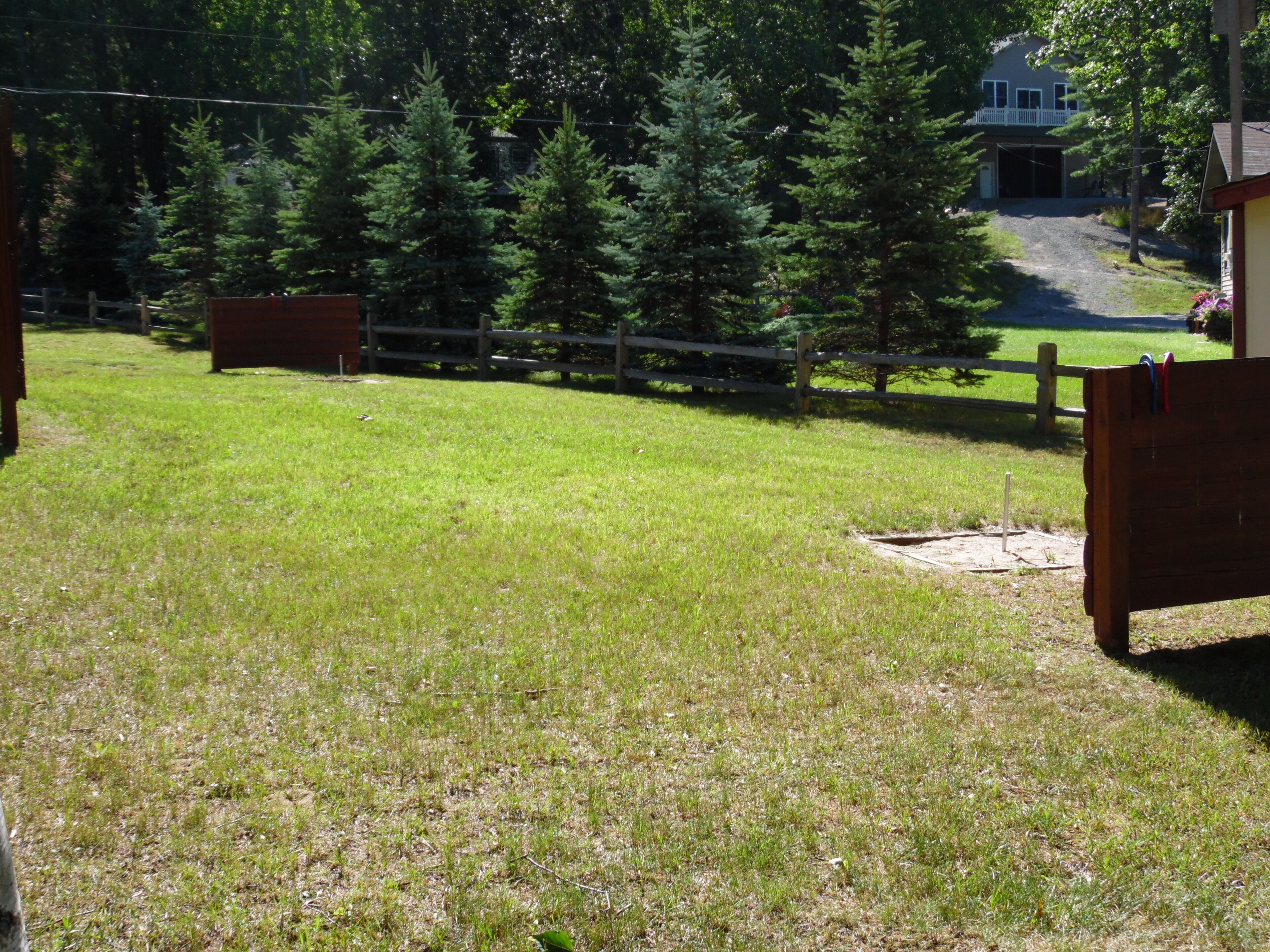 A grassy outdoor area with wooden fences and trees.