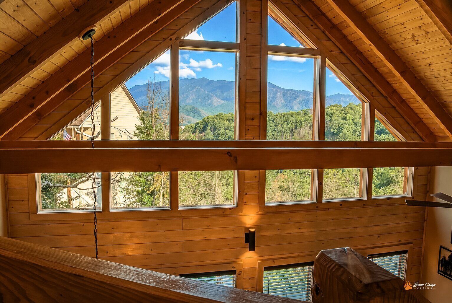 A cabin with a high ceiling and large windows offering a mountain view.