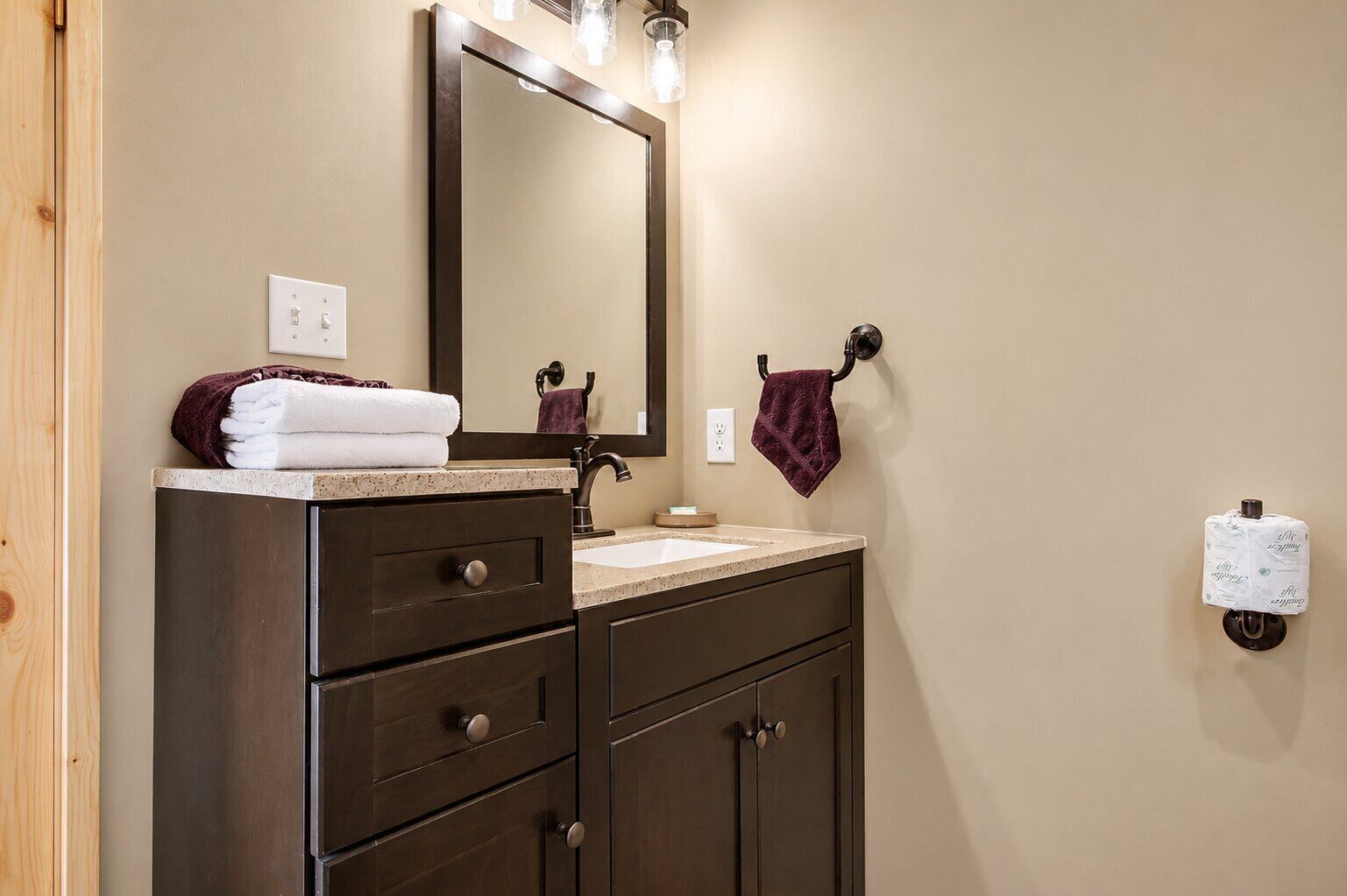 A bathroom with a dark wooden vanity, a mirror, a sink, and a towel rack.