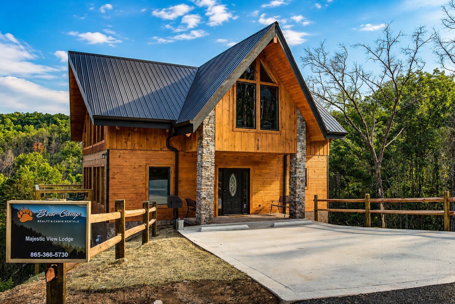 A two-story lodge with a stone entrance, a covered porch, and a signboard advertising realty and cabin rentals.