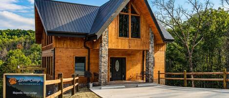 A two-story lodge with a stone entrance, a covered porch, and a signboard advertising realty and cabin rentals.