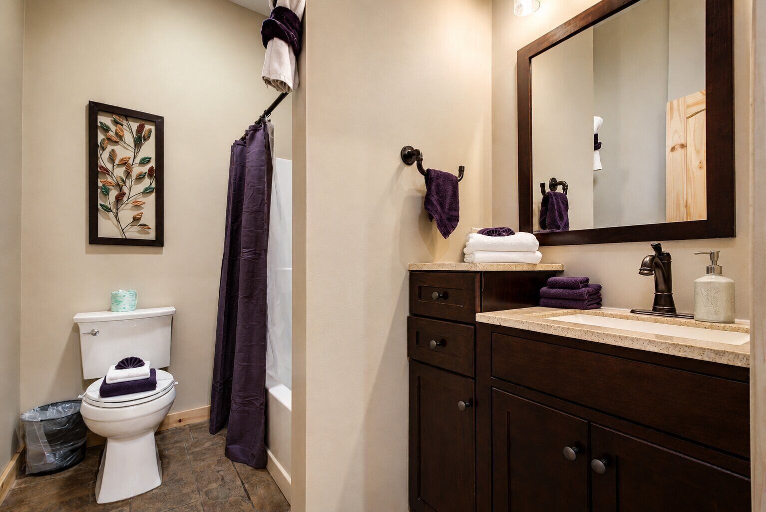 A bathroom with a toilet, a shower curtain, a sink with a mirror, and a cabinet.