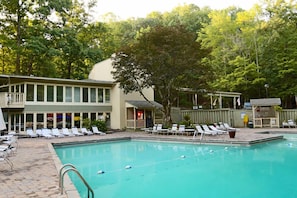 A pool area with lounge chairs and a building with a balcony.