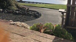 A paved pathway leading to a coastal view with a rocky garden and a wooden gate. - Beachfront Cottage with Fantastic View (Crescent City)
