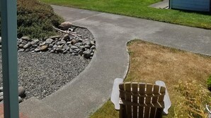 A covered porch with a view of the ocean, a paved pathway, and a chair. - Beachfront Cottage with Fantastic View (Crescent City)