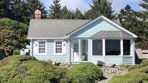 A light blue house with a grey roof, surrounded by dense greenery and trees. - Beachfront Cottage with Fantastic View (Crescent City)
