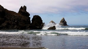 A coastal scene with rocky formations and waves crashing onto the shore. - Beachfront Cottage with Fantastic View (Crescent City)