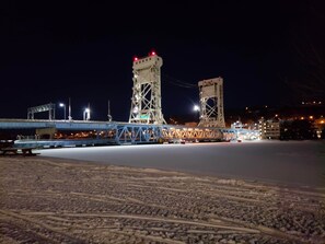 Een nachtzicht van een brug met twee torens, een weg onderdoorgang en een met sneeuw bedekte grond.