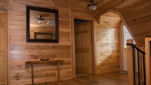 Un interior de madera con un espejo, una mesita y una escalera.