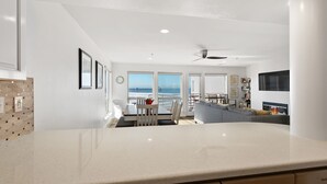 Una cocina moderna con una isla grande, comedor con vistas y sala de estar con televisión y asientos.