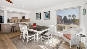 Una cocina moderna con armarios blancos, una isla central y un comedor con mesa y sillas.