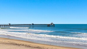 Una playa con un muelle que se adentra en el océano.