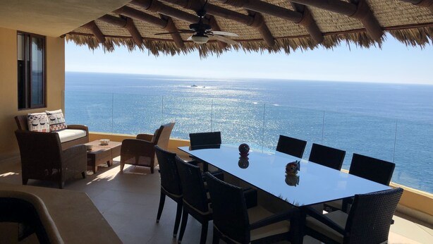 A dining area with a glass table and chairs, overlooking a scenic ocean view. - 3,400 sqft OCEANFRONT 3 BDR 4 BTR AMAZING CONDO. 900SQFT TERRACE STUNNING VIEWS (Ixtapa)