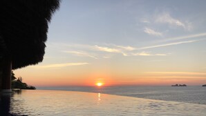 A sunset over a calm sea with a clear sky, a pool, and a rocky coastline. - 3,400 sqft OCEANFRONT 3 BDR 4 BTR AMAZING CONDO. 900SQFT TERRACE STUNNING VIEWS (Ixtapa)