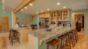 A spacious kitchen with a large island, wooden bar stools, and built-in cabinetry.