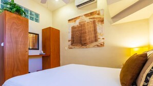 Ein Hotelzimmer mit einem Bett, einem Holzschrank, einer Wandklimaanlage und einem gerahmten Bild.