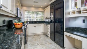 A modern kitchen with white cabinetry, a black refrigerator, and a granite countertop. - Somewhere... for Birding and Boating (Dunnellon)