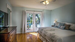 A bedroom with a bed, a dresser, a ceiling fan, and a sliding glass door leading to an outdoor area. - Somewhere... for Birding and Boating (Dunnellon)