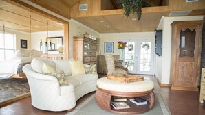 A spacious living room with a large white sofa, a wooden coffee table, and a hanging plant. - Panoramic Water Views, Deep Water Dock, Right outside Your Doors! (Midway)