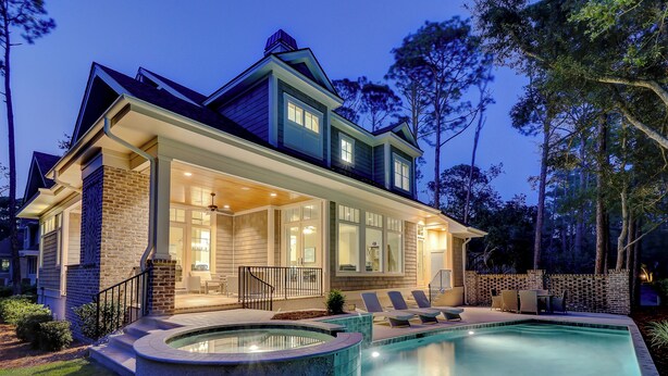 Uma casa de dois andares com piscina, área de estar ao ar livre e um pátio bem iluminado.