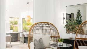 Un salon moderne avec des fauteuils en osier, une table basse ronde et un grand miroir.