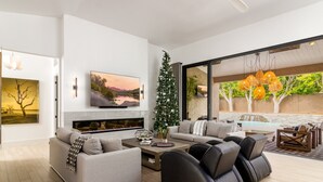 Un salon moderne avec une cheminée, un grand téléviseur à écran plat et un sapin de Noël.