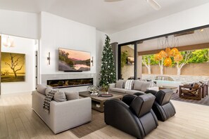 A modern living room with a fireplace, a large flat-screen TV, and a Christmas tree. - SWSS 3BR Kierland Indoor-Outdoor Desert Living | Heated Pool, Hot Tub, Fire Pit & 30‑Day Minimum (Scottsdale)