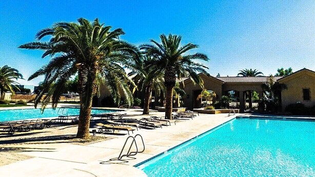 A swimming pool with lounge chairs and palm trees, surrounded by buildings. - Country Club 1092 heated pool, 1000 feet from Golfland Sunsplash Amusement Park (Mesa)