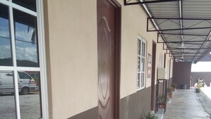 A building with a covered walkway, a wooden bench, and potted plants. - Guestroom Langkawi (Langkawi)
