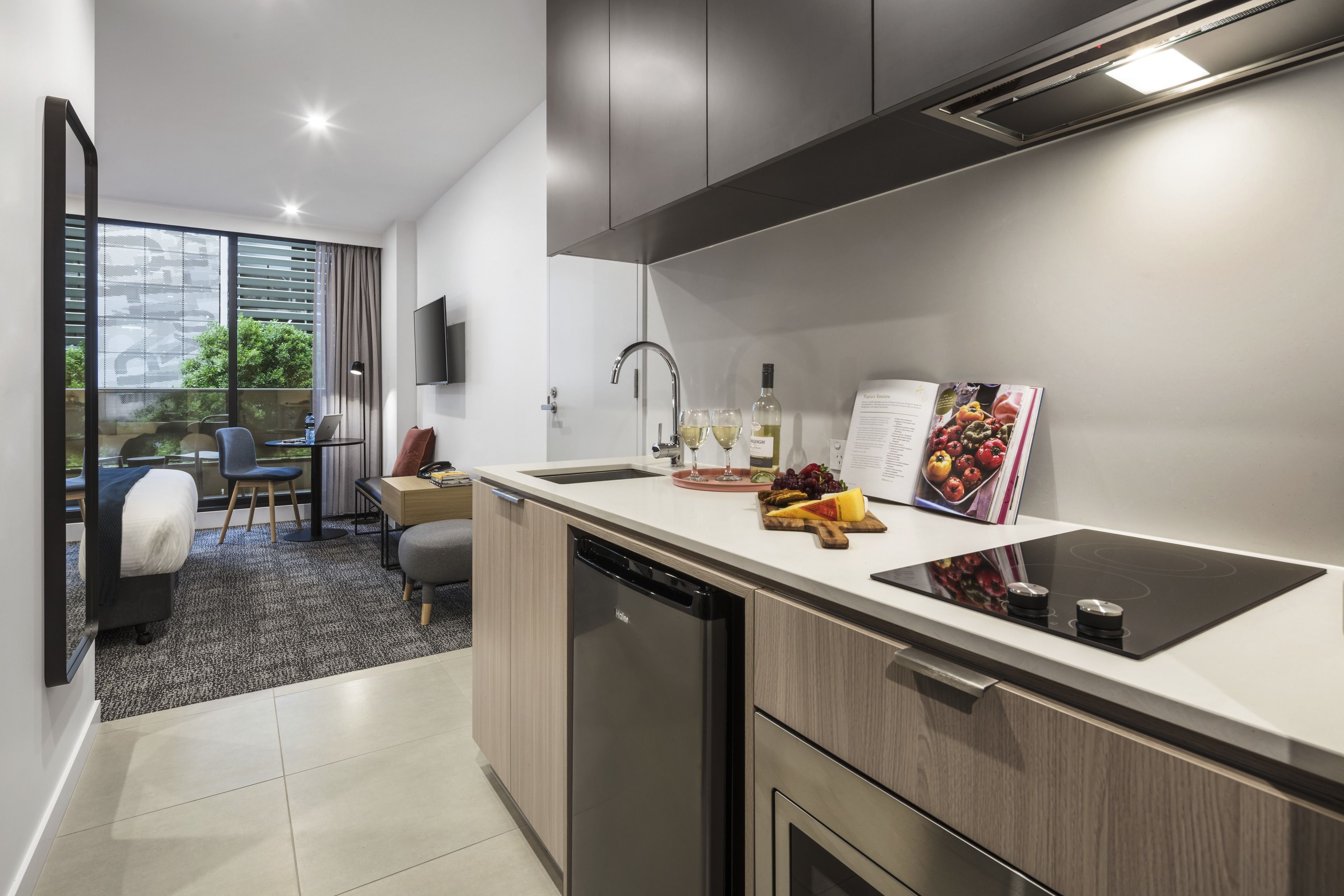 A modern kitchen with a dishwasher, a built-in stove, and a dining area with a table and chairs.