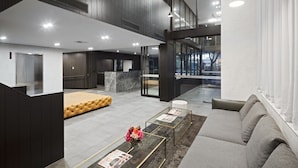A modern lobby with a sofa, coffee table, and a reception desk. - Quest NewQuay (Docklands)