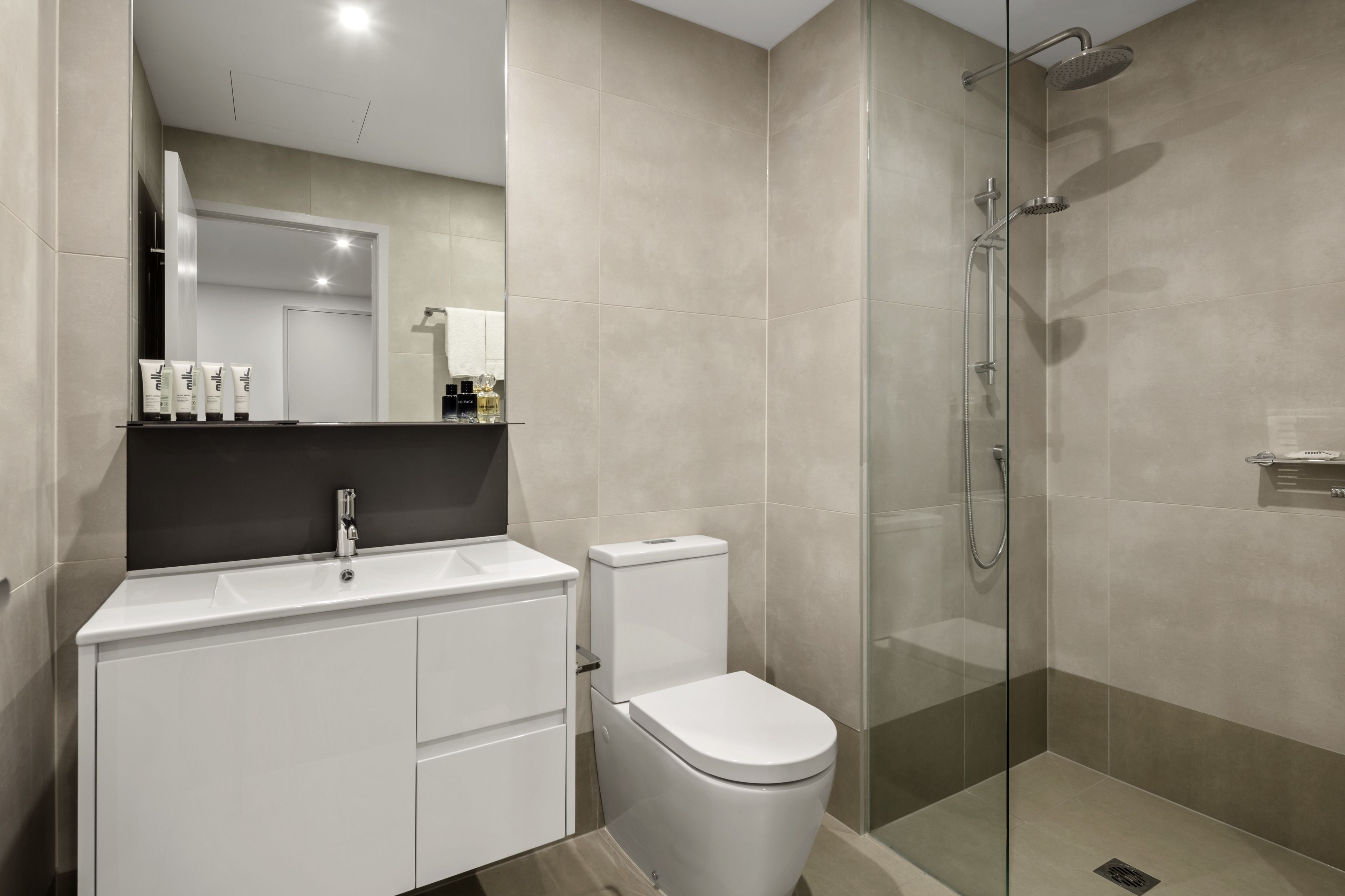 A modern bathroom with a glass-enclosed shower, a white sink, and a toilet.