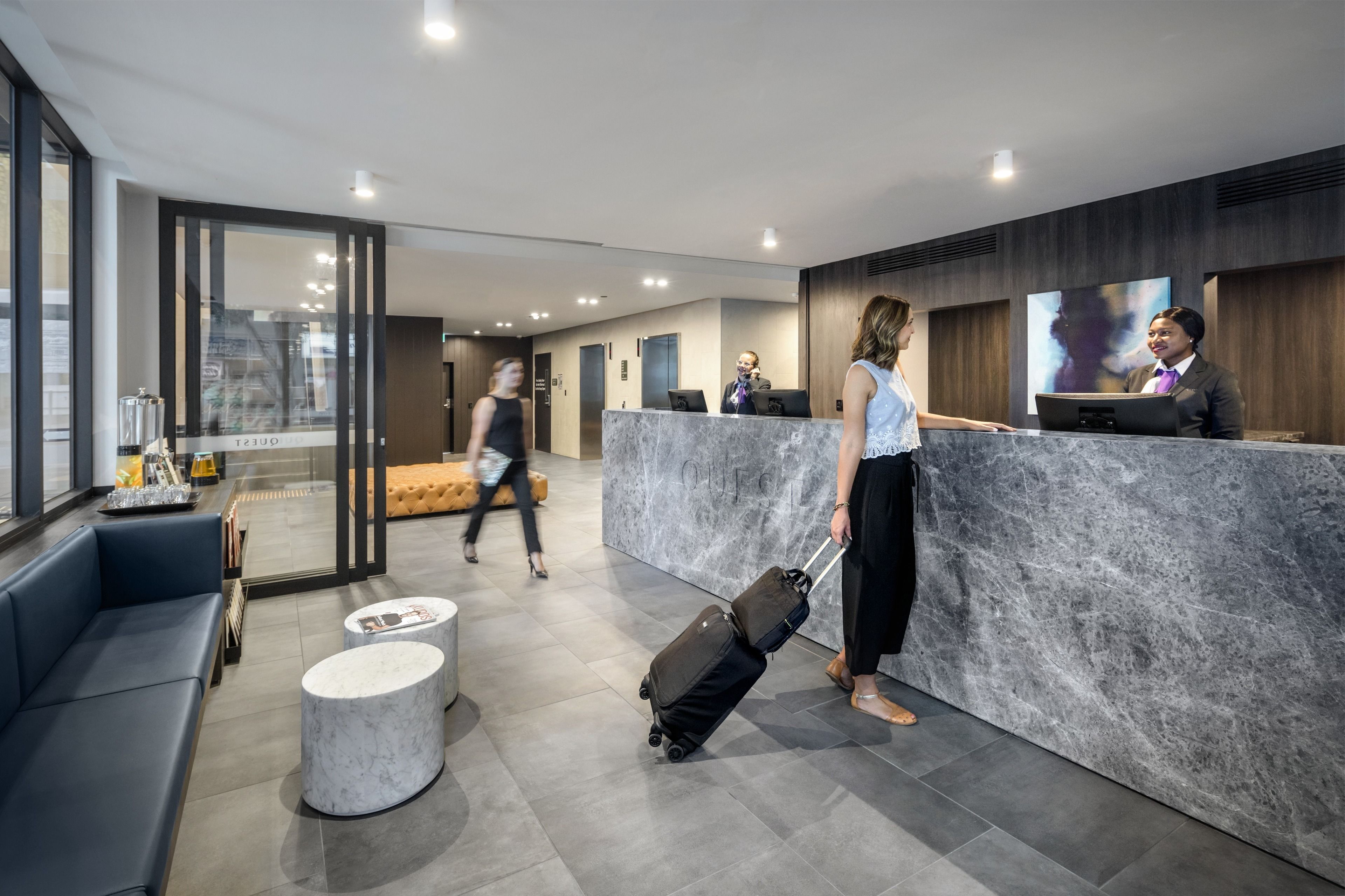 Un espace d’accueil moderne, avec un comptoir en marbre, un canapé et une table basse.