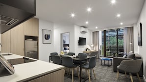 A modern hotel room with a kitchenette, a dining area, a living space, and a large window offering a view. - Quest NewQuay (Docklands)