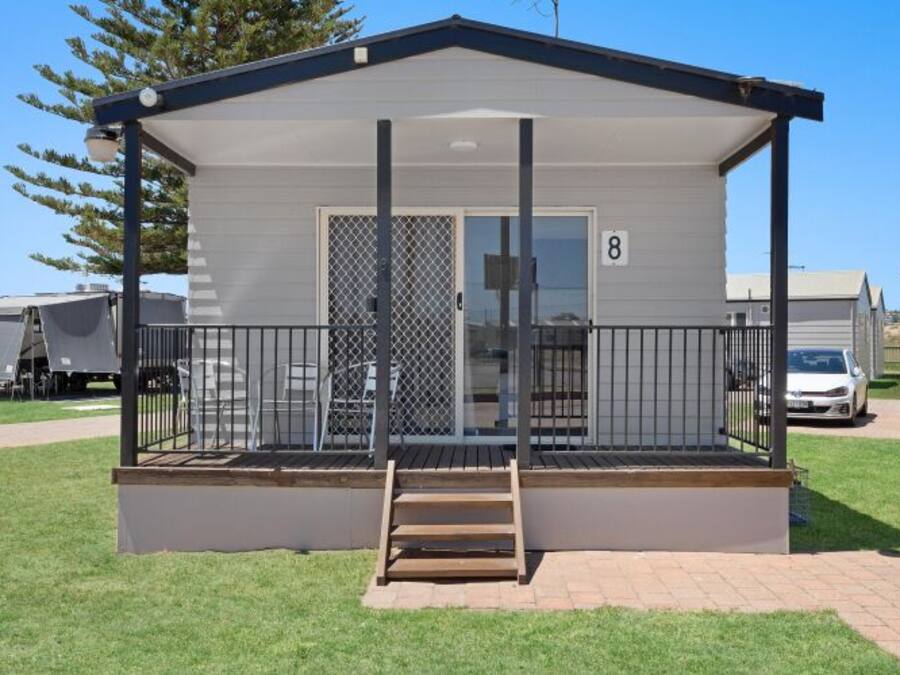 A single-story mobile home with a covered porch, a front door, and a number '8' on the side.