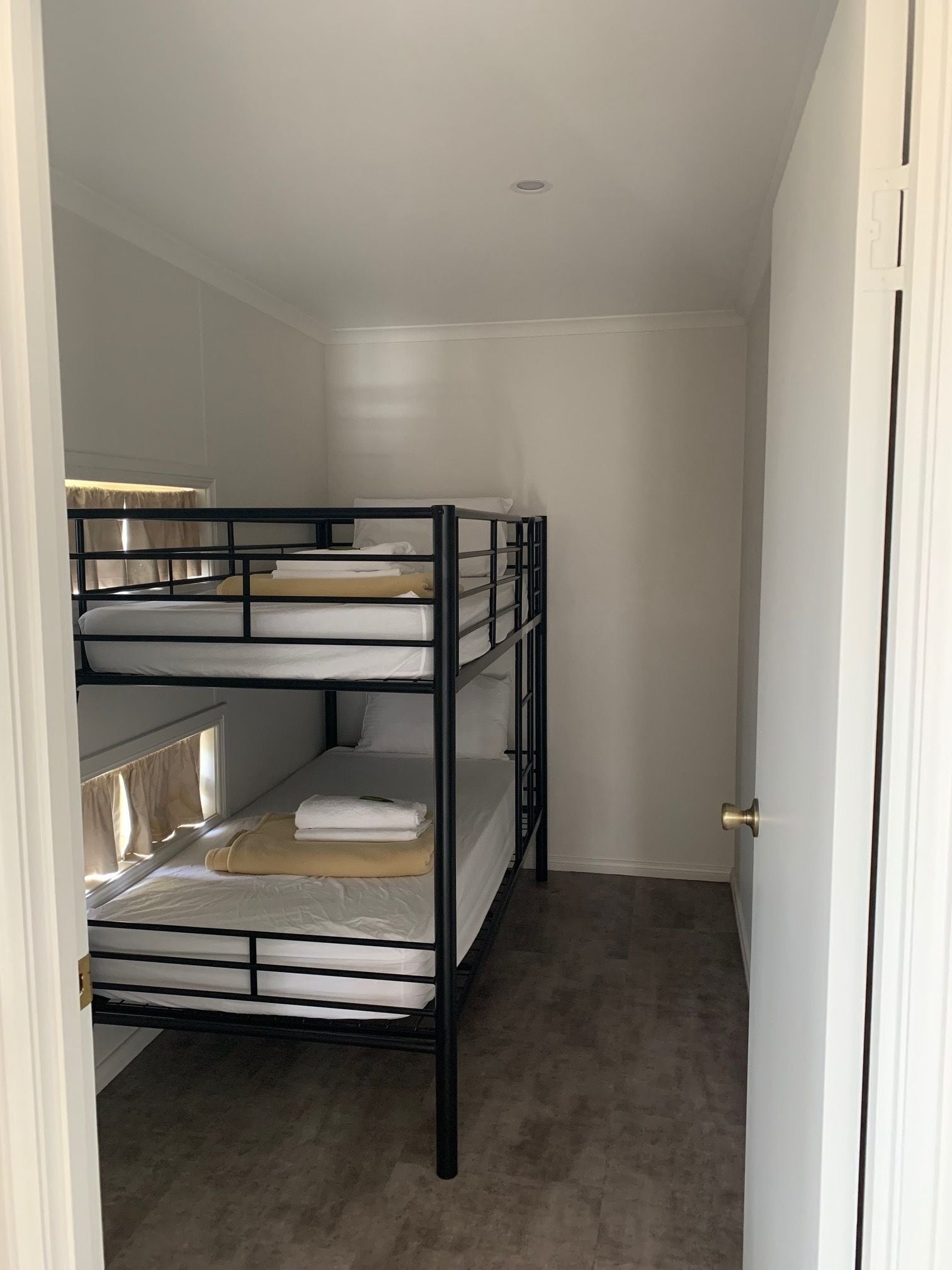 A compact, three-tiered bunk bed room with a simple, clean design.