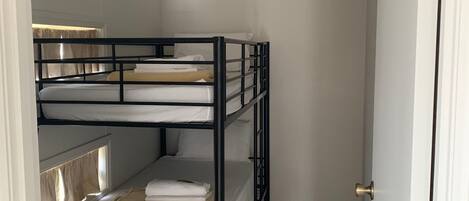 A compact, three-tiered bunk bed room with a simple, clean design.