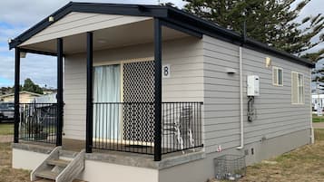 A single-story mobile home with a covered porch, a fenced patio, and a number '8' sign.