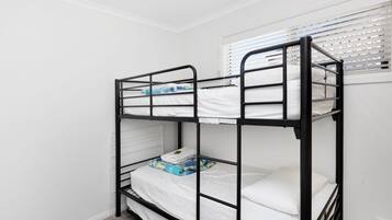 Una cama litera con ropa de cama blanca y una pequeña caja en la cama inferior.