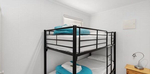 A bunk bed with a window, a bedside table with a lamp, and a wall-mounted light switch. - Moana Beach Tourist Park (Moana)
