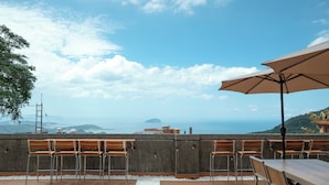 A rooftop terrace with wooden furniture, a table, and an umbrella. - Jiufen The Dragon Easy Stay (New Taipei City)