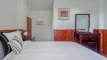 A hotel room with a large bed, a wooden dresser, a mirror, and a framed picture on the wall.