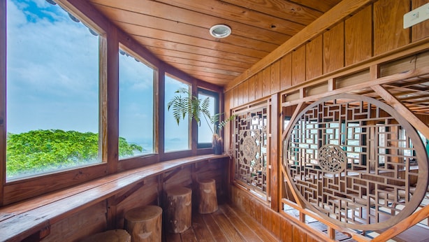 A wooden interior with large windows, wooden stools, and traditional lattice screens. - Jiufen The Dragon Easy Stay (New Taipei City)