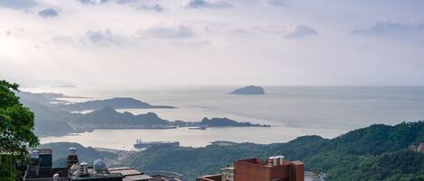 A panoramic view of a coastal city with buildings, a bay, and a distant island.