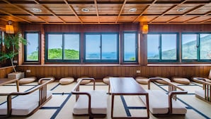 A traditional Japanese-style room with tatami flooring, wooden furniture, and large windows offering ocean views. - Jiufen The Dragon Easy Stay (New Taipei City)